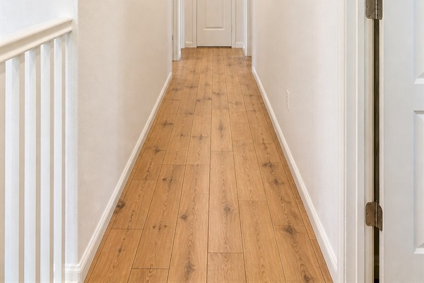 Bright second-floor hallway with natural wood flooring connecting all bedrooms