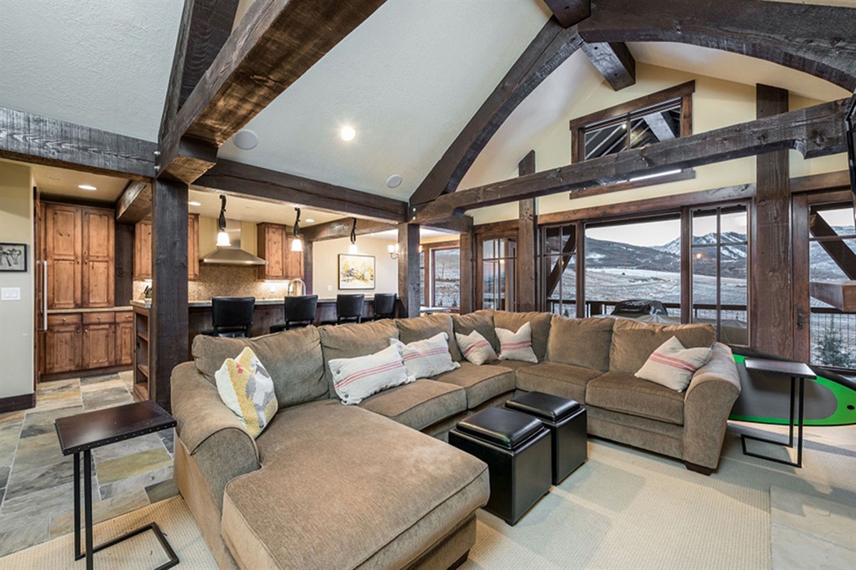 An inviting living room anchored by dramatic beams and warm finishes, offering a sophisticated gathering space designed for both comfort and style.