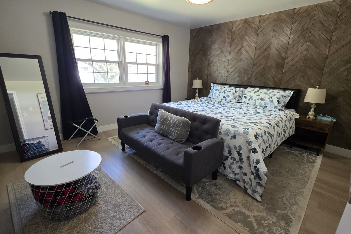 Your comfortable escape: primary bedroom. King bed with TV, pull-down couch, desk, soft carpet, dresser, closet, USB lamps, and cozy robes.