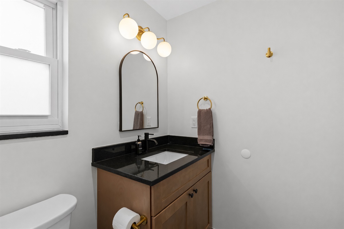Modern bathroom vanity with sleek black countertop, warm wood cabinetry, and stylish lighting—perfect for a fresh, comfortable start to your day.