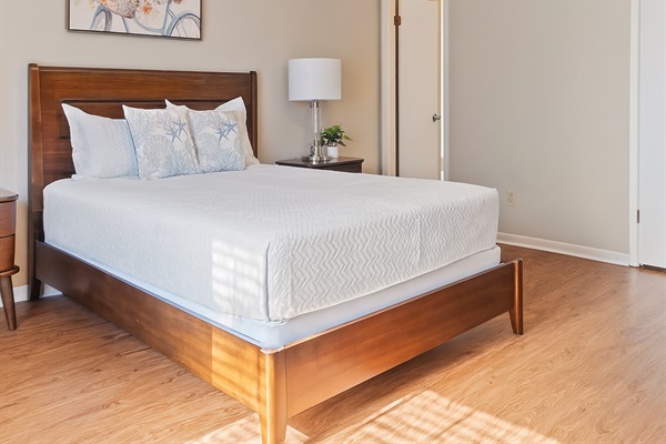This bedroom features a cozy queen bed with soft linens, modern bedside lighting, and calming decor — perfect for a restful night’s sleep. The neutral tones and natural light create a warm and inviting atmosphere for your stay.