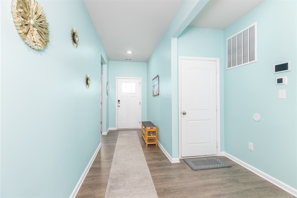 Step into a sunlit foyer painted in coastal hues, with a durable runner rug and convenient bench—perfect for shedding sandy shoes and greeting guests.