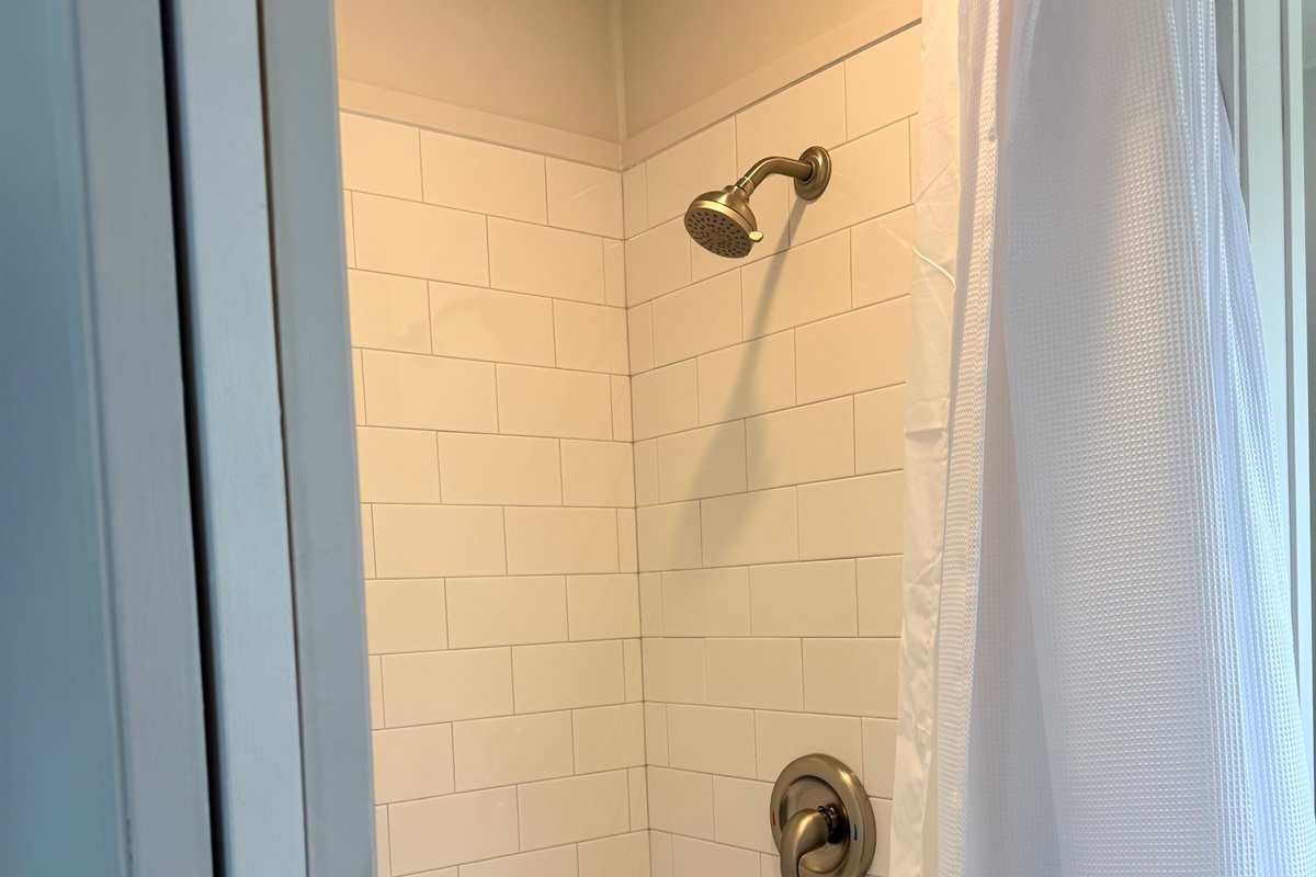 Nice size bathroom with shower, sink and residential toilet