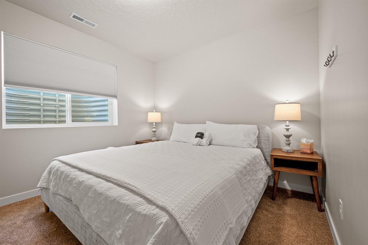 A comfortable queen bed, soft lighting, and bedside tables make this downstairs bedroom a welcoming retreat.