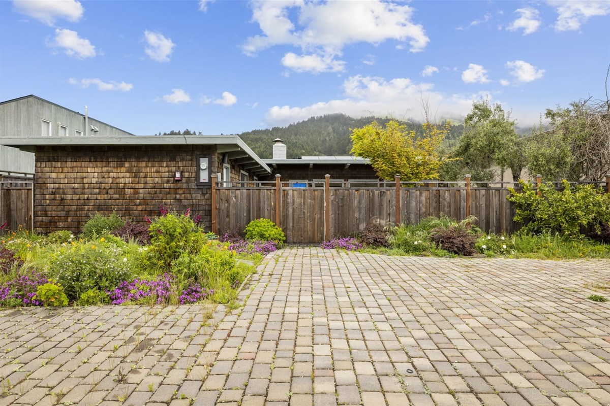 Driveway and front garden with colorful blooming plants.

