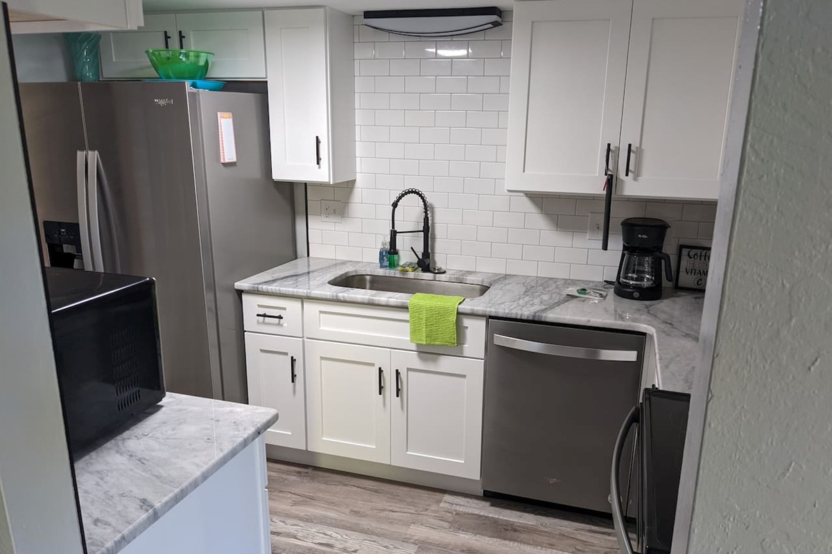 Granite countertops, stainless steel appliances, large sink, many kitchen gadgets, pots, pans, and utensils.