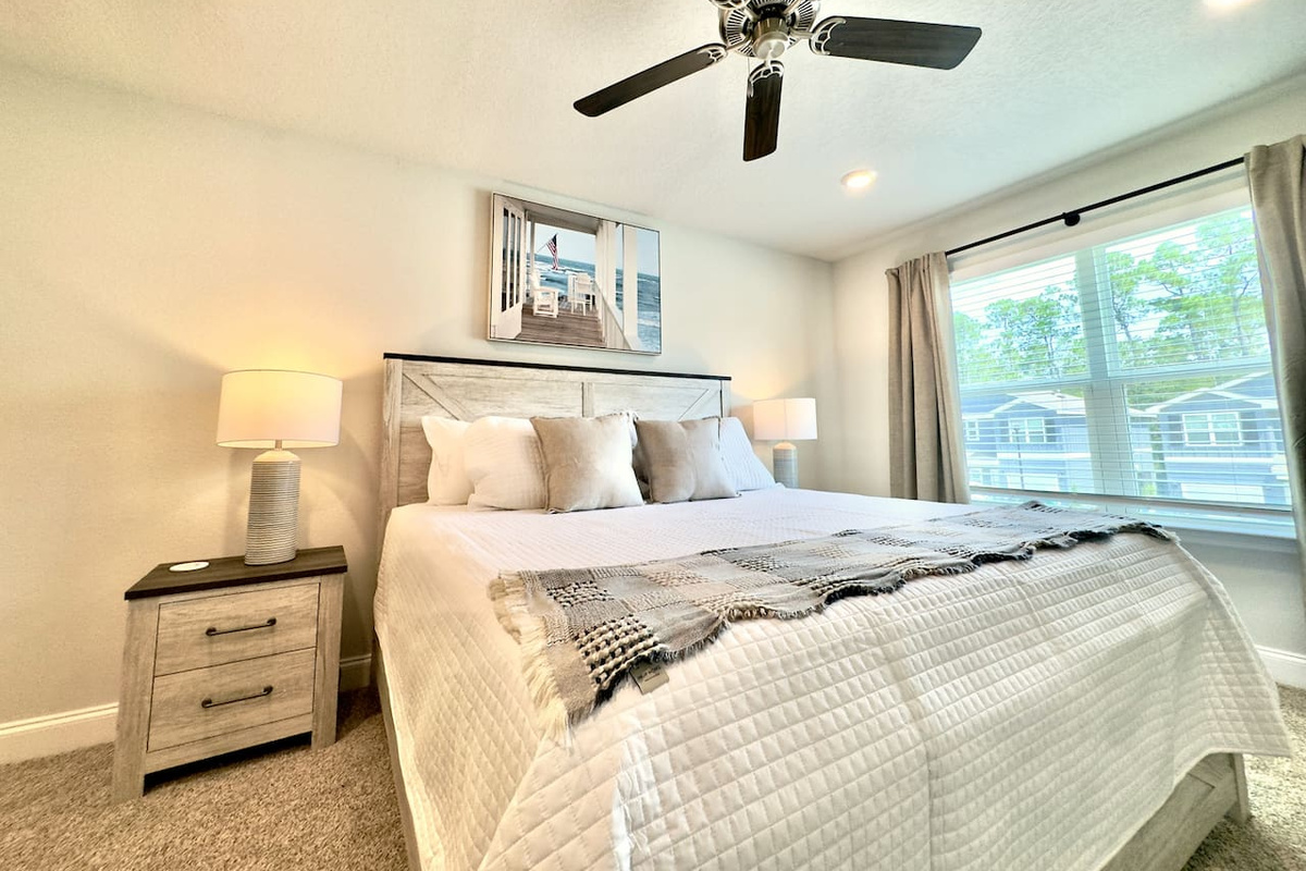 After a long day, this bed pulls you in — soft pillows, weighted comfort, carpet cushioning tired feet. Fan humming gently; eyes grow heavy, ready to rest.