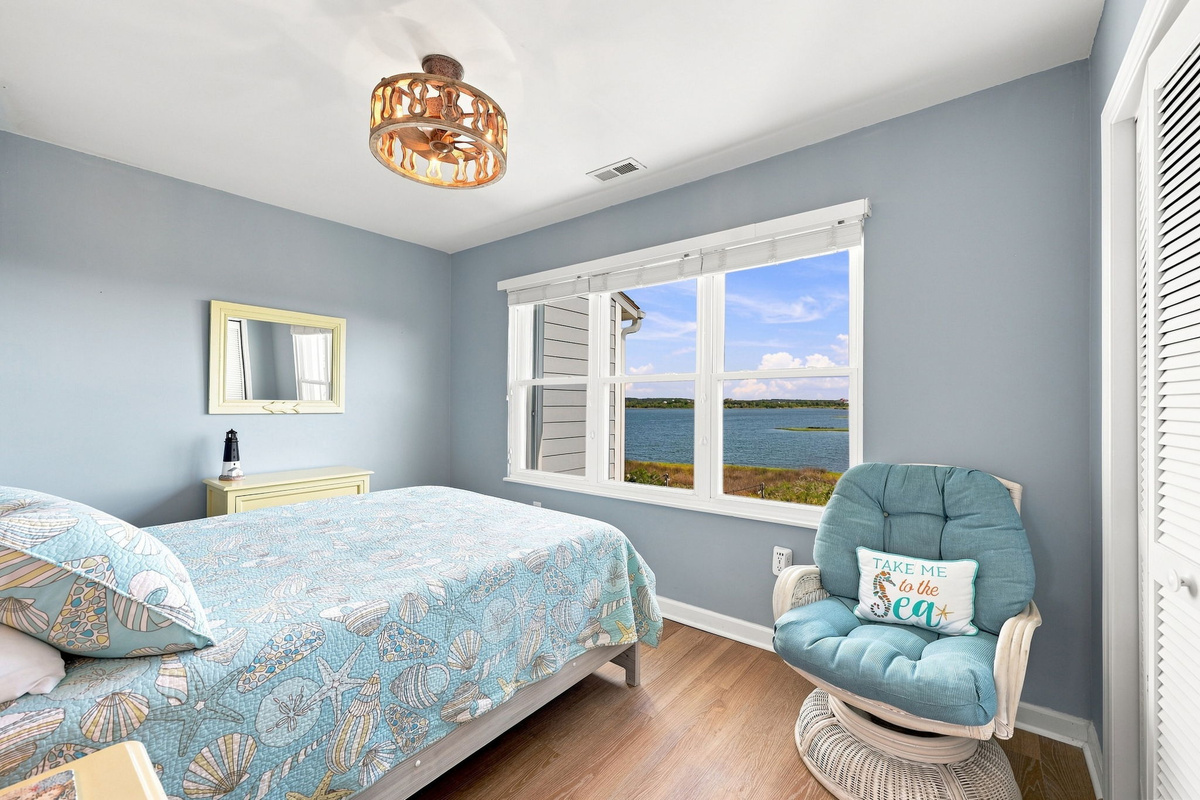 Wake up to gorgeous water views and a refreshing coastal breeze in this serene, sunlit bedroom.