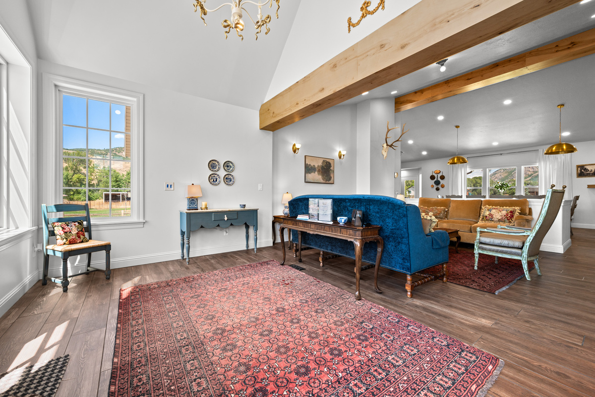A striking entry opens into a light-filled interior with soaring ceilings, exposed wood beams, layered furnishings, and refined mountain-inspired character.
