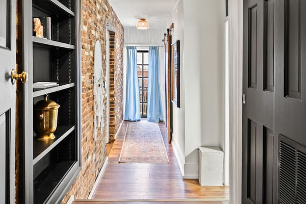 Hallway from kitchen to guest bedrooms and bath. Original exposed brick. 