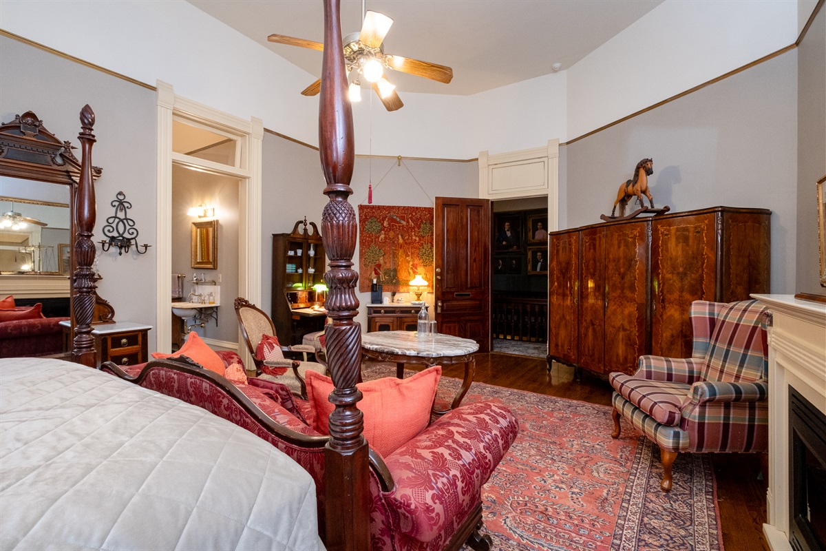 Four-poster king bed, antique wardrobe, hardwood floors, and classic Victorian furnishings.