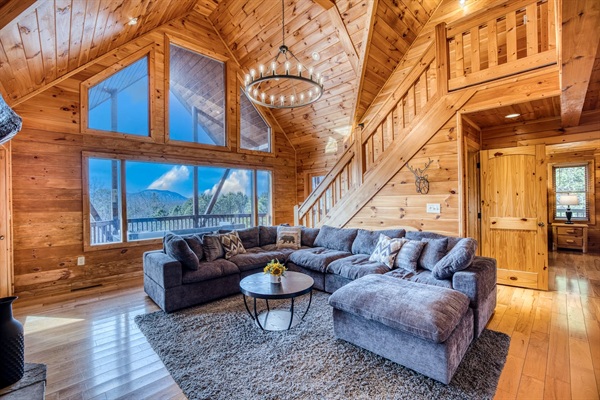 Main living room with beautiful A-frame ceiling, wall of windows, double-sided gas fireplace, and stunning mountain views! 