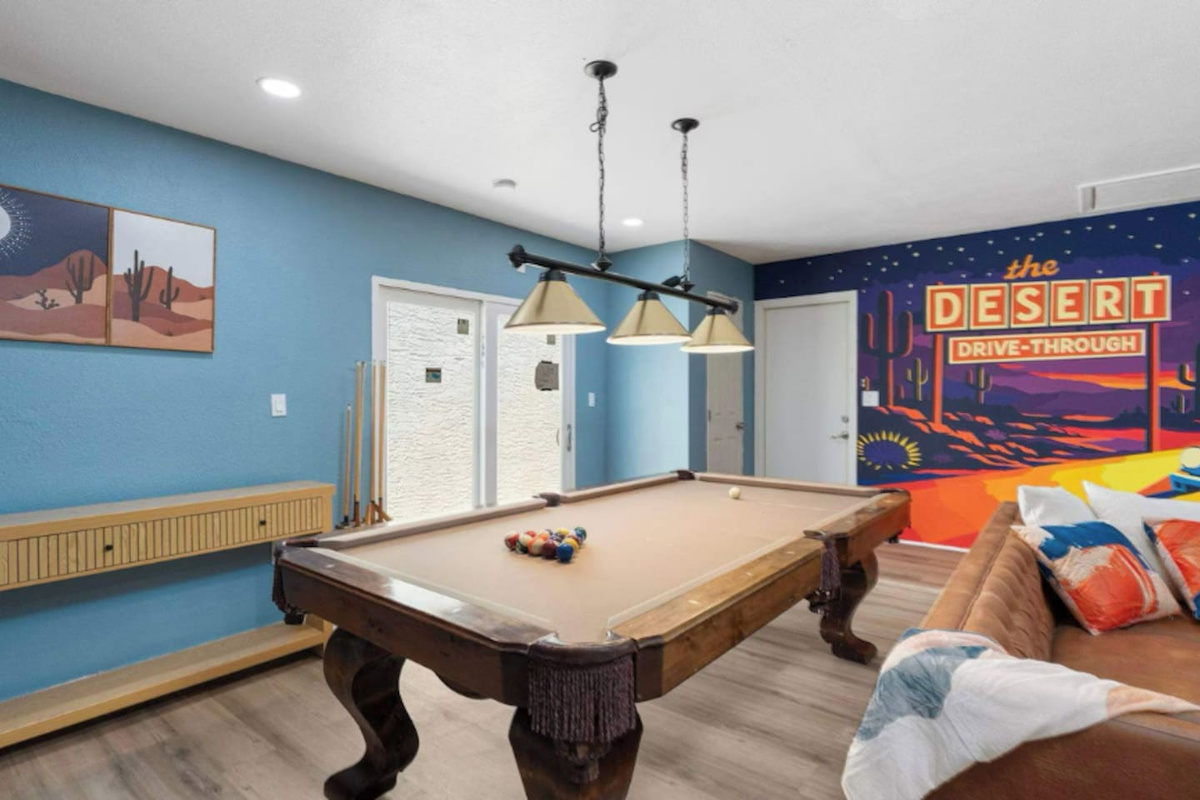 Entertainment lounge with pool table, vintage desert mural, blue walls, and seating—a fun, laid-back hangout for guests.