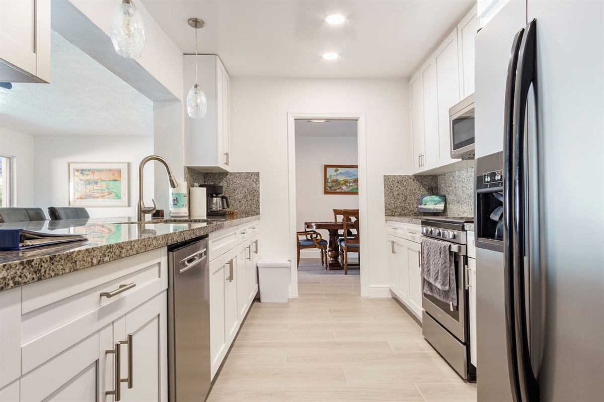 View from the kitchen toward dining room. Kitchen cupboards are stocked with cookware,dishware, glassware, table settings for the dining room, as well as plastic-ware for poolsidedining.