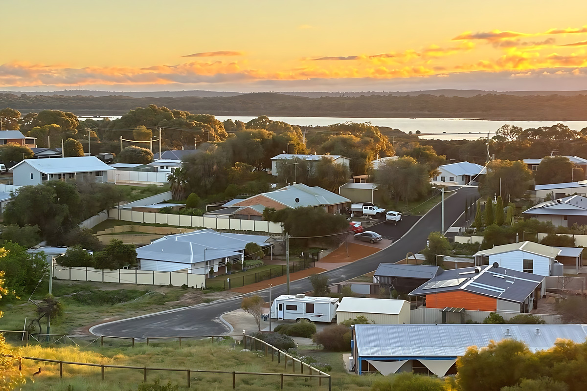 Sunset from Lake Views & Coastal Escape, looking over the rooftops of Preston Beach to Lake Preston, with the bushland of Yalgorup National Park stretching along the far shore.