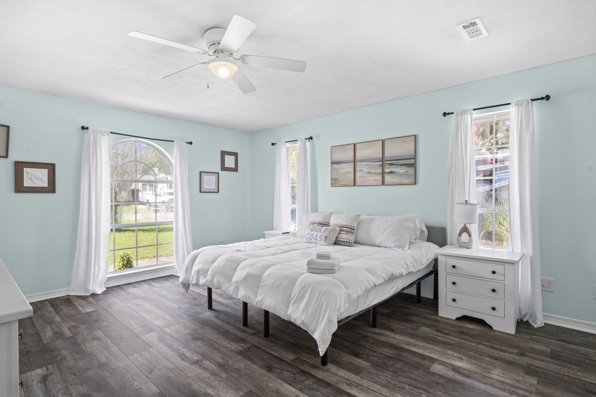 A serene seafoam-blue retreat with a plush king bed, arched windows, and plenty of natural light.