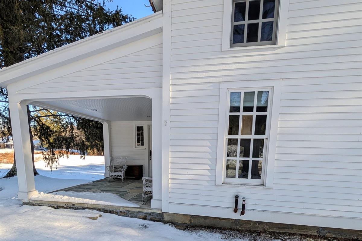 Elegant farmhouse façade featuring a covered entryway and timeless architectural details.
