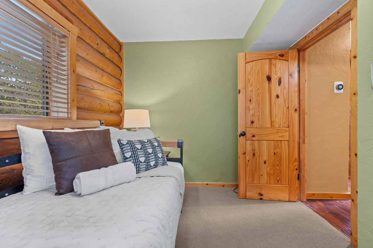 Additional view of the twin bedroom with warm wood trim and natural light.