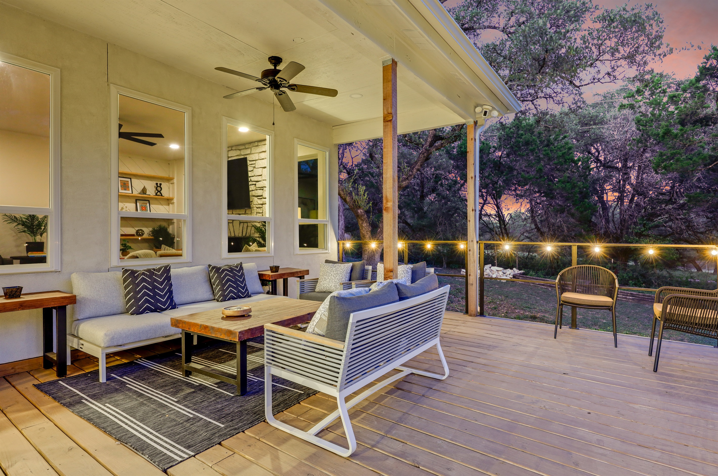 Enjoy serene evenings on this cozy covered porch, complete with a ceiling fan, plush seating, and warm lighting for the perfect post-dinner unwind.