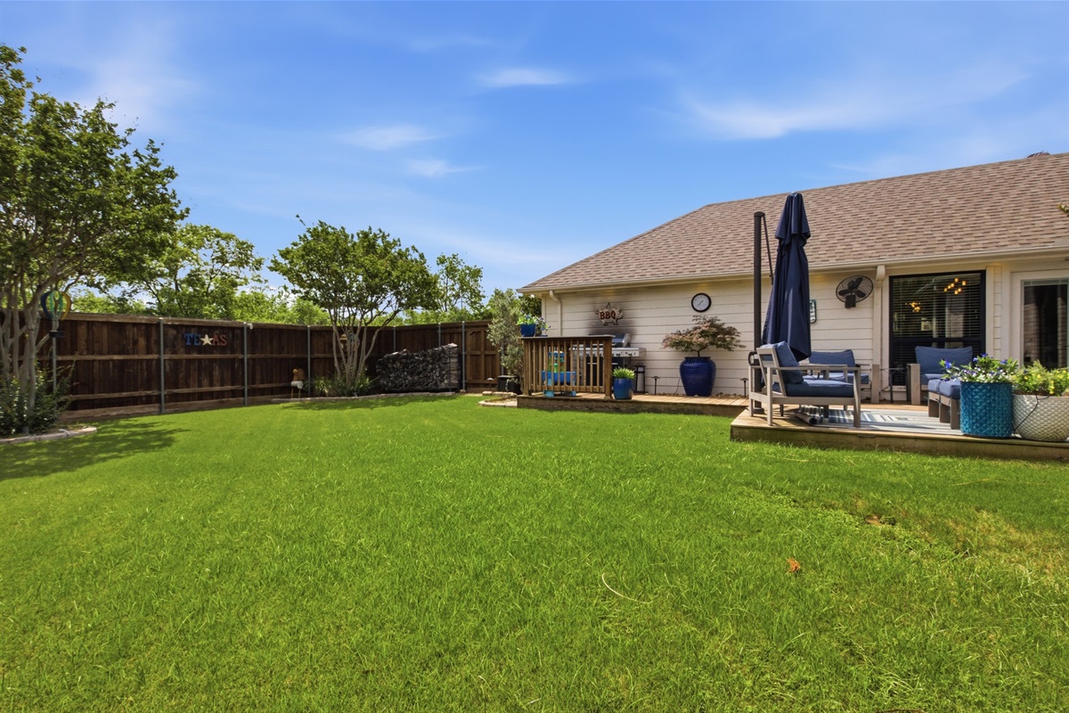 Fully fenced private Backyard with mature trees and total privacy backing up to no rear neighbors. Multi-level wooden Deck, propane BBQ Grill, and multiple Outdoor seating areas with shade umbrellas.