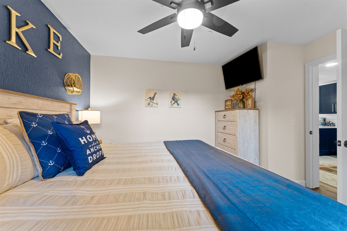 Comfortable bedroom with mounted TV and dresser storage.