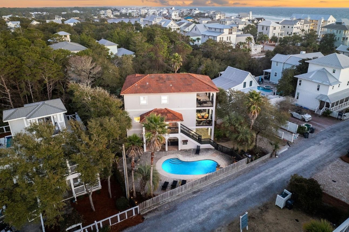 Bird's-eye perspective of your 30A vacation home highlighting the private backyard pool, ample paver parking, and coastal surroundings