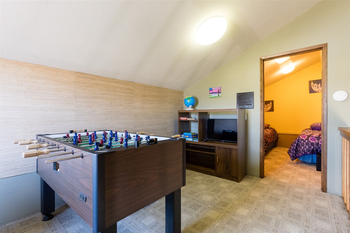 Loft recreation space with foosball, TV, board games, and beds..