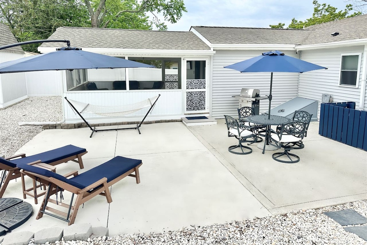 Maximize your vacation in our fully equipped backyard. Features include a gas grill, patio dining for four under a blue umbrella, lounge chairs for sunbathing, and a relaxing hammock. The perfect setup for a summer afternoon BBQ!