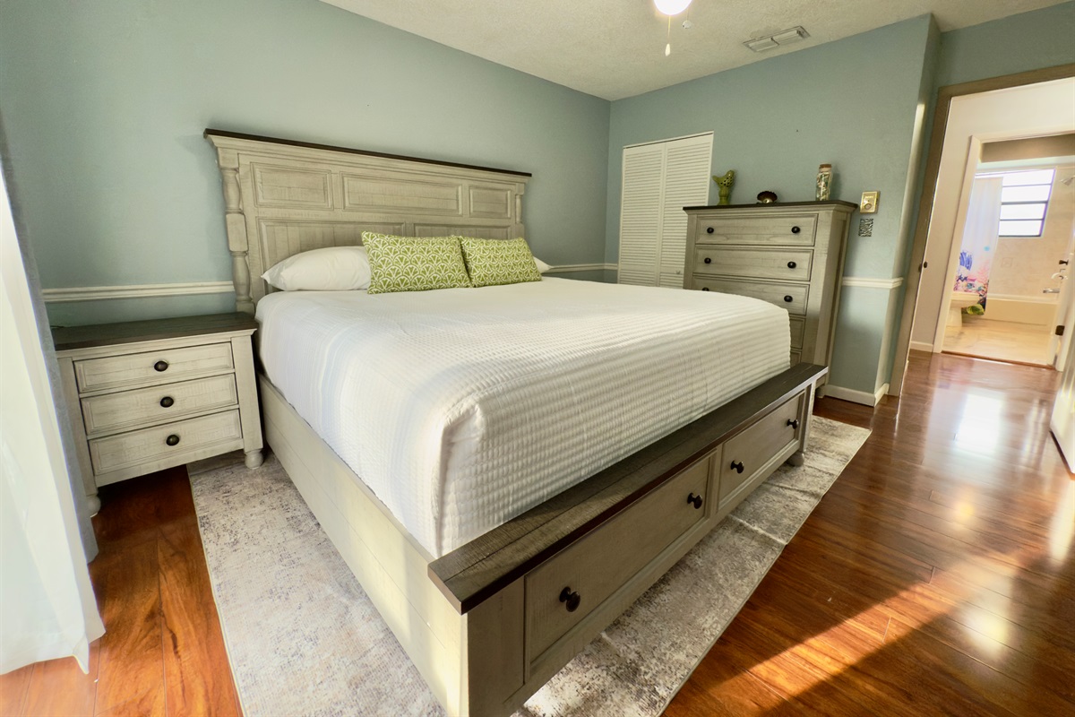 Featuring a sumptuous king-size bed with a detailed wood-paneled headboard and coordinating bedside tables.