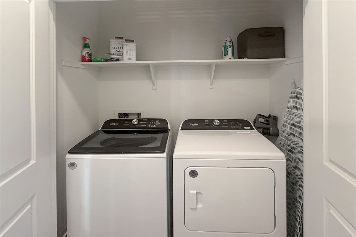 Laundry closet with washer, dryer, shelf, and supplies