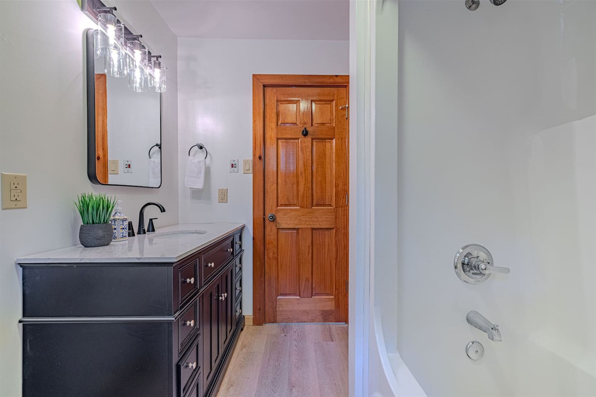 Thoughtfully updated with a sleek new vanity and contemporary finishes, this upstairs full bath offers a tub/shower combo and dual access for added convenience.