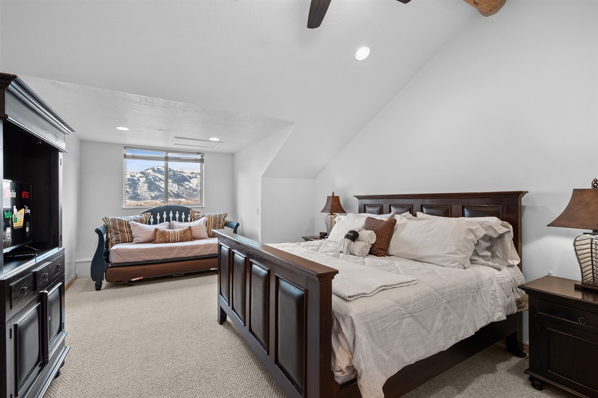 Spacious primary bedroom with vaulted ceilings, king bed, and cozy seating for quiet moments or winding down.