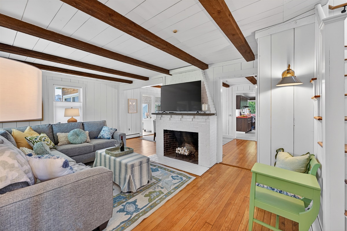 Side perspective of the living room revealing the seating area alongside the TV and fireplace.
