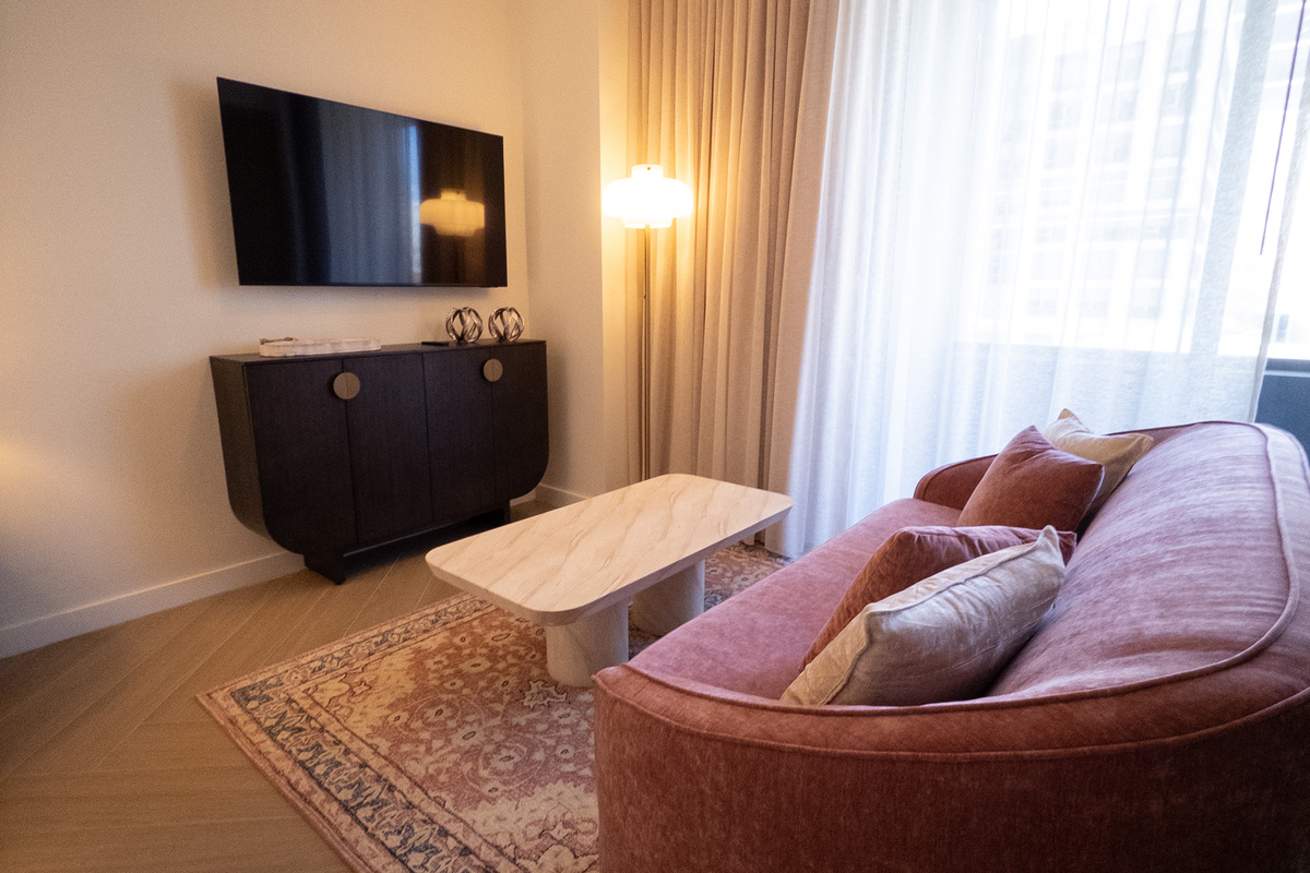 Living area with smart TV, rose-velvet sofa and a travertine table for easy nights in.