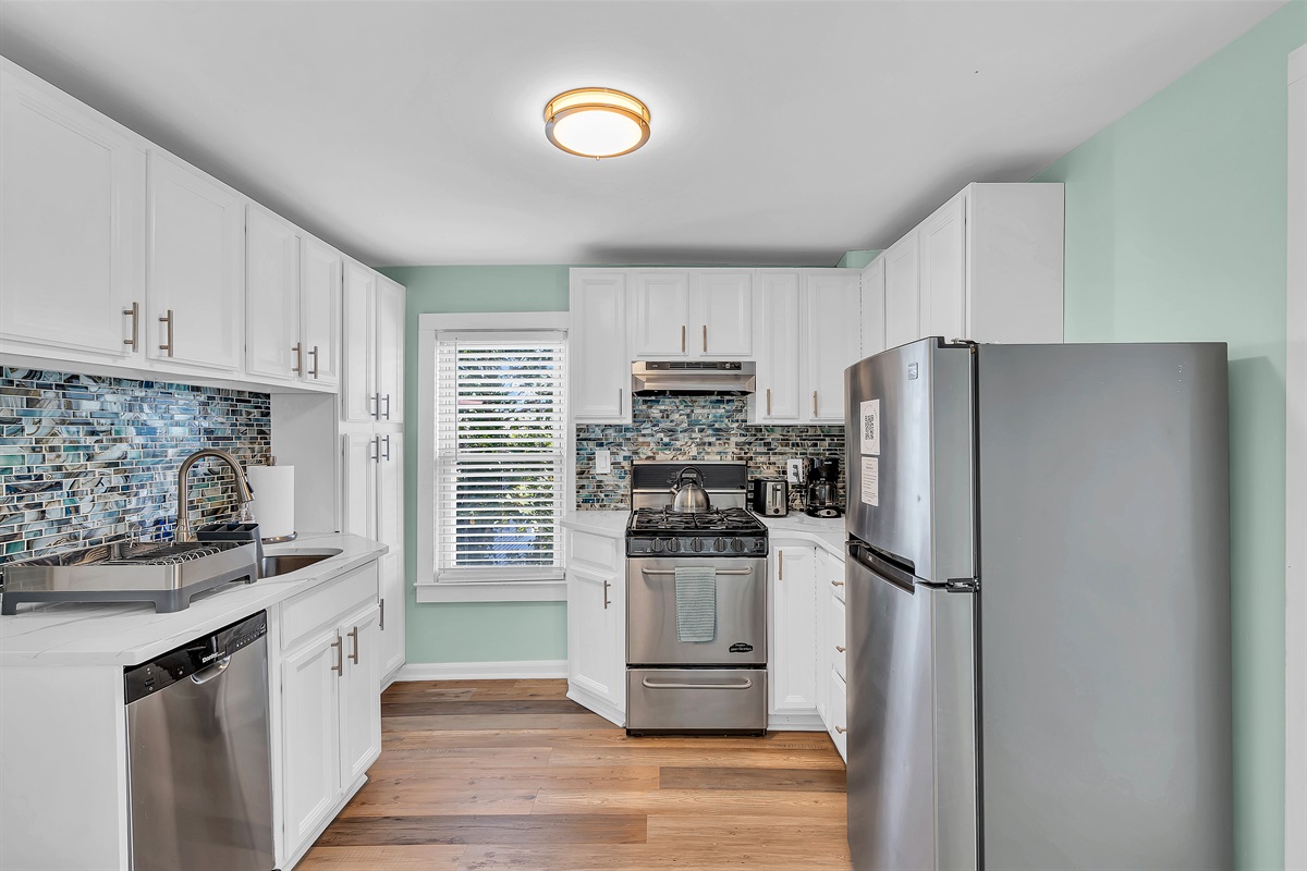 Cook in style at The Embury Retreat's fully equipped kitchen. Modern appliances, ocean-inspired backsplash, and ample space for preparing Jersey Shore favorites. Steps from Ocean Grove beach and Asbury Park dining