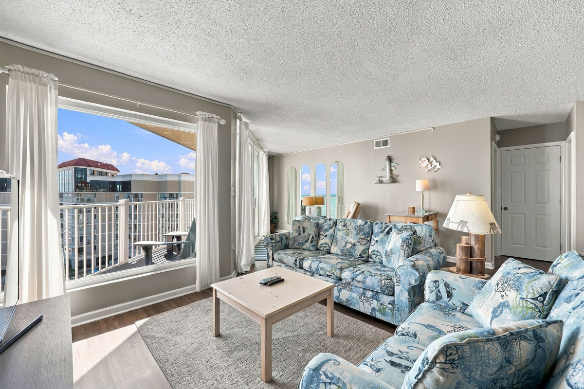 Cozy living area featuring a floral-patterned sleeper sofa, a coffee table, and large sliding glass doors leading to a private balcony.