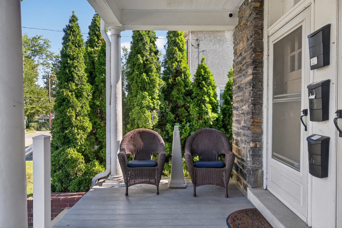Deep, shared front veranda with outdoor seating and designated outdoor smoking area.