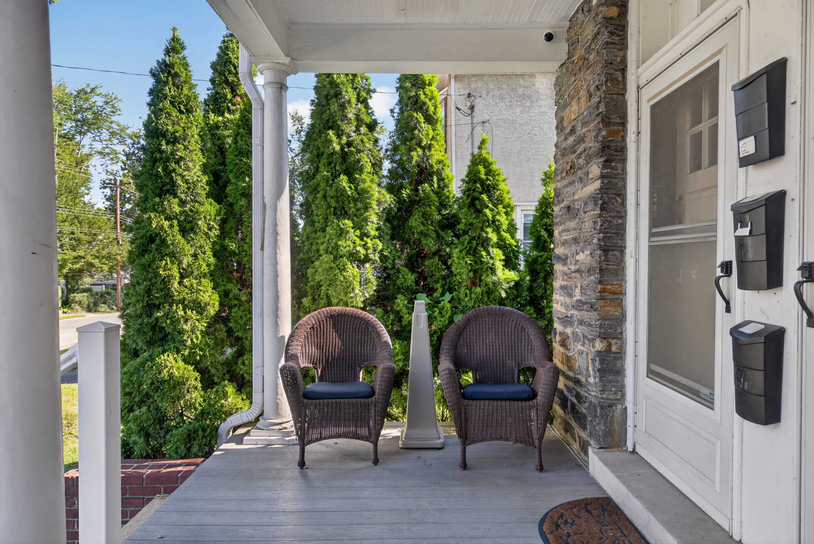 Deep, shared front veranda with outdoor seating and designated outdoor smoking area.