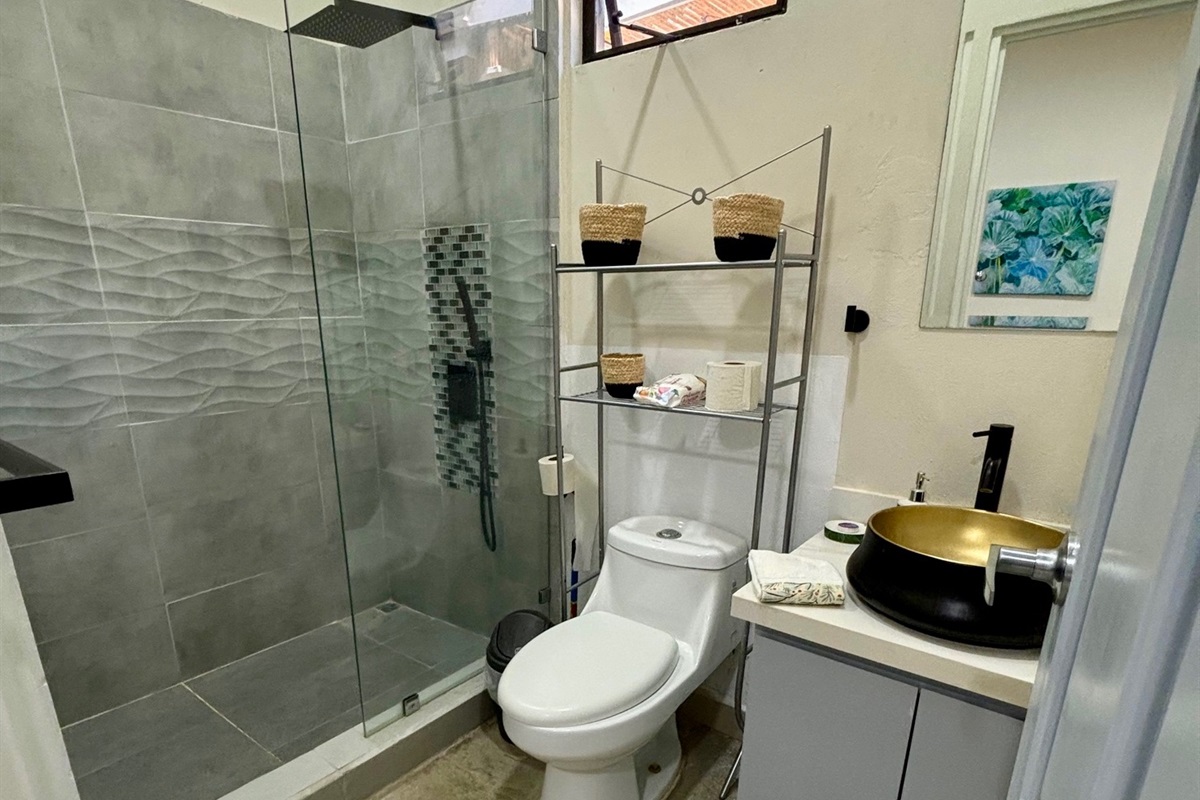 The second bathroom has a tiled walk-in rain shower and copper sink