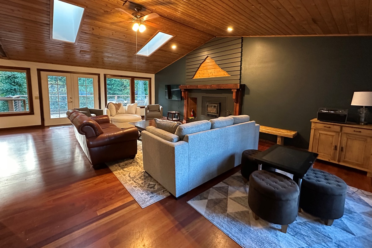 Natural light streams into the large gathering room with huge windows & skylights. Snuggle up for a movie, gather around the woodburning fireplace, listen to music on the record player, or play  the Infinite Game table... there's something for all!