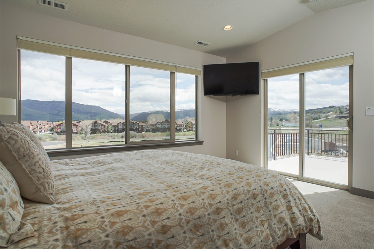 A serene queen bedroom with expansive windows showcasing breathtaking mountain views, creating a peaceful retreat filled with natural light.