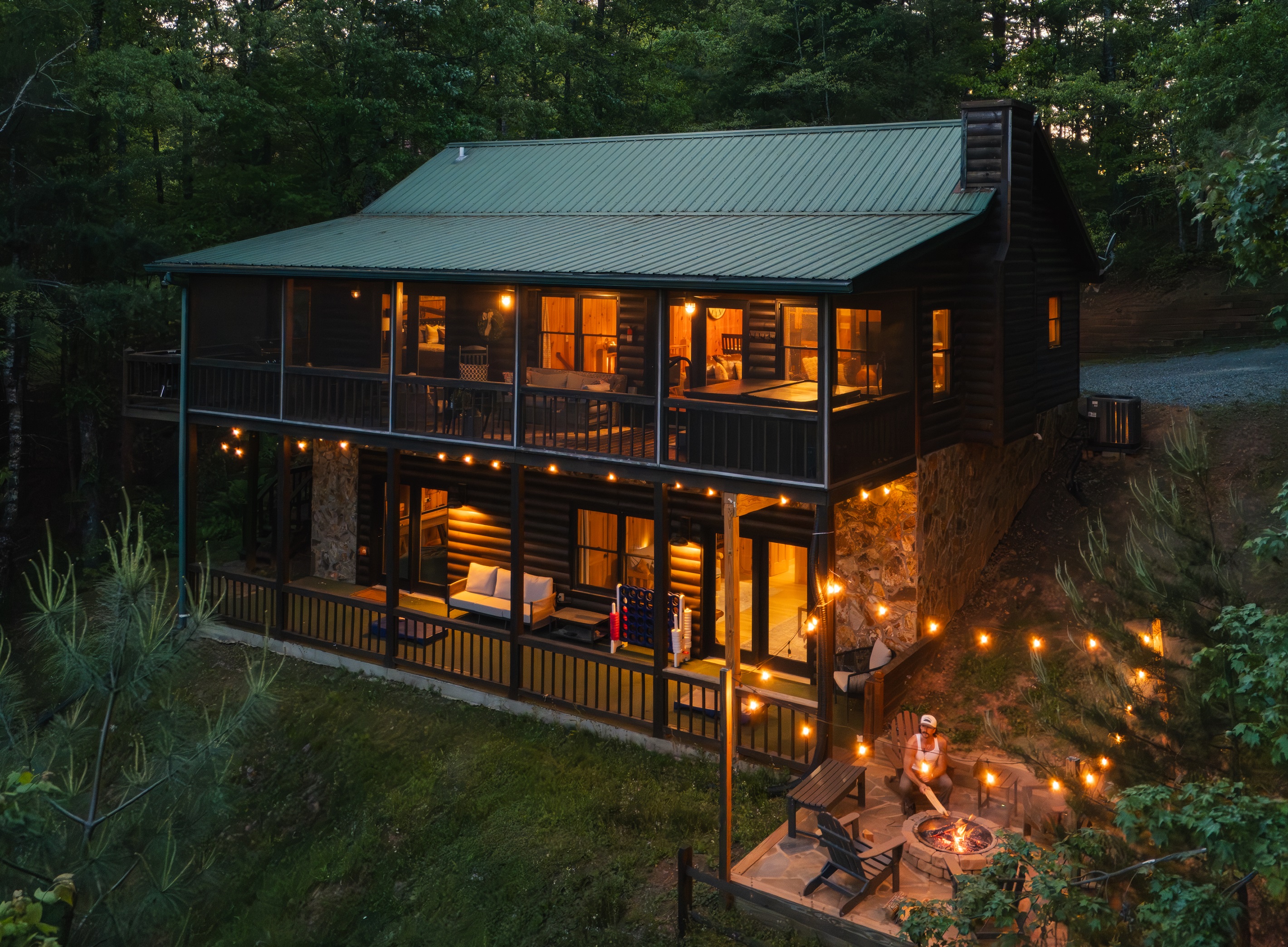 🔥 Nightfall at Cooper’s Ridge. Multi-level outdoor living with mountain views. Guests can enjoy panoramic scenery from the private hot tub, screened-in porch, or while gathered around the fire pit with string lights.