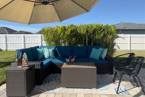 Patio lounging with oversized adjustable umbrella, fire pit table.