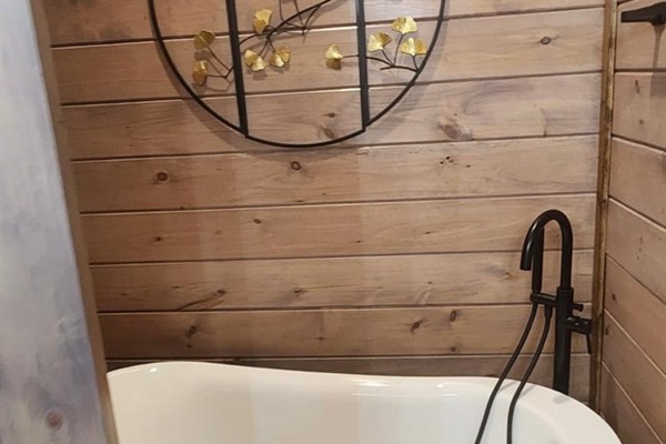 Classic clawfoot soaking tub with black fixtures for a relaxing bath.