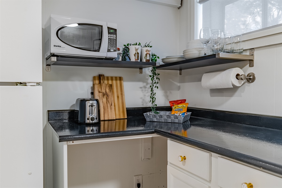 Compact prep space with microwave, toaster, kettle, and essentials for light meals and take-out.