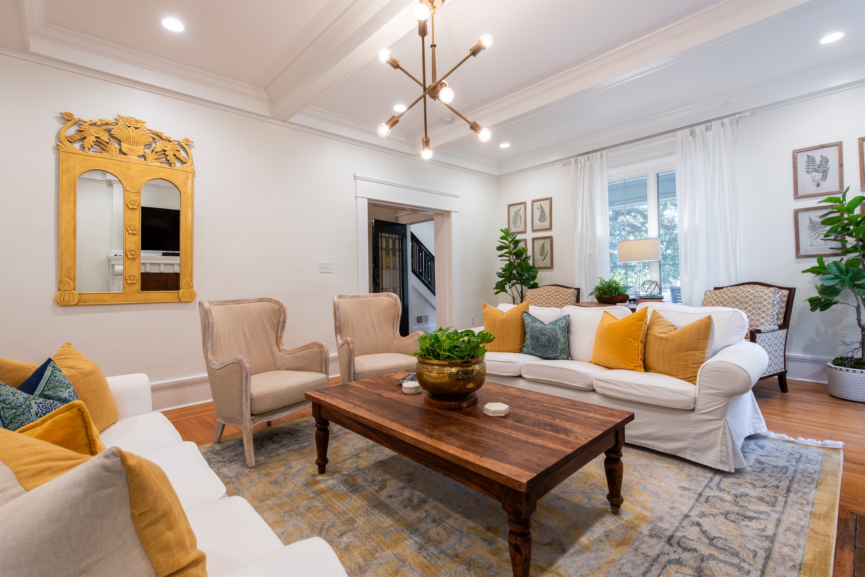 Enjoy this bright living room on the Bourbon Trail in Louisville Highlands! Cozy seating, a modern chandelier, and lush plants perfect spot to relax after exploring Kentucky’s distilleries.