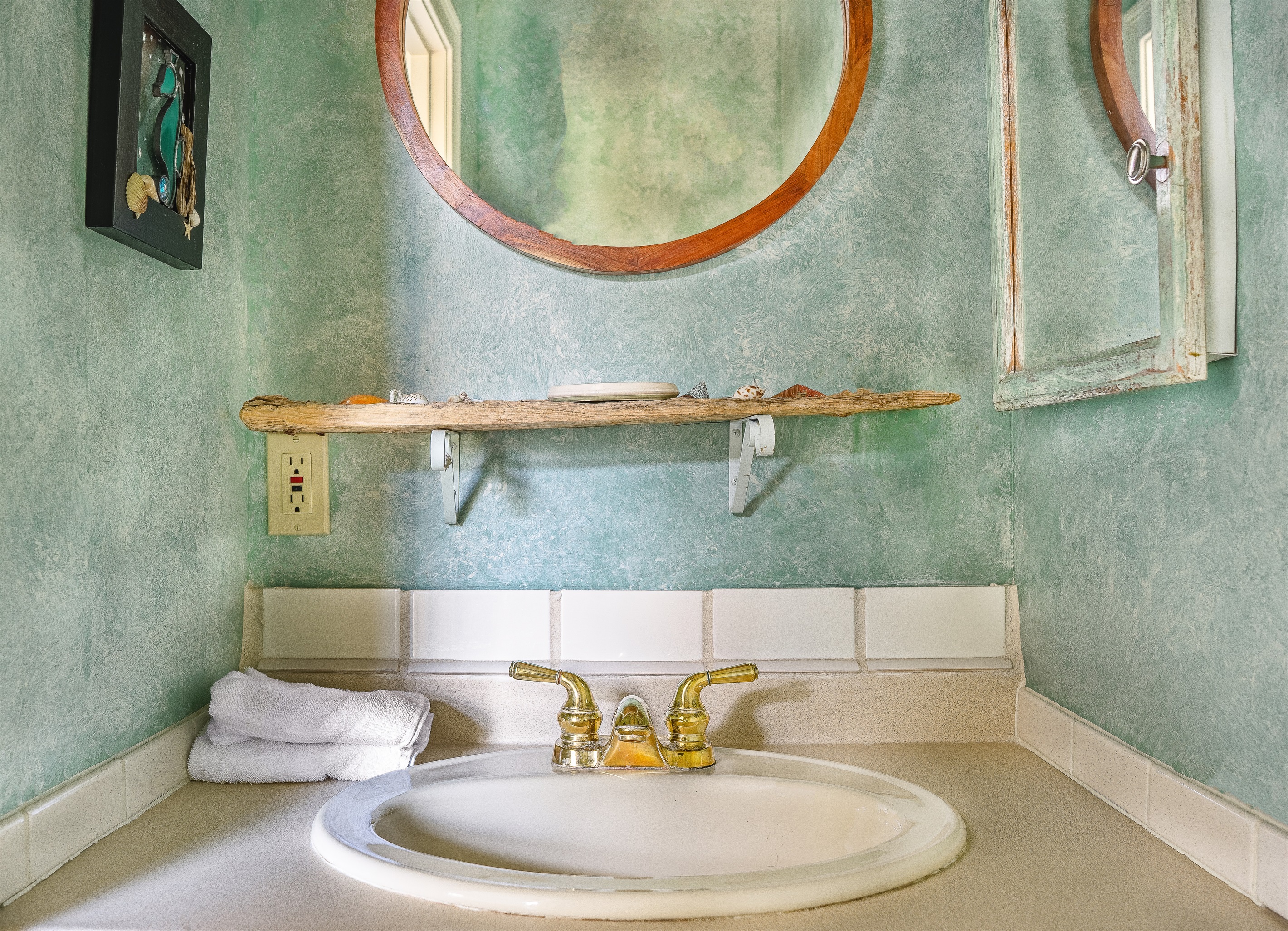 The convenient main floor half-bath features unique coastal textures and a custom driftwood shelf. This thoughtfully designed powder room ensures comfort and accessibility for your group without needing to head upstairs during the day.