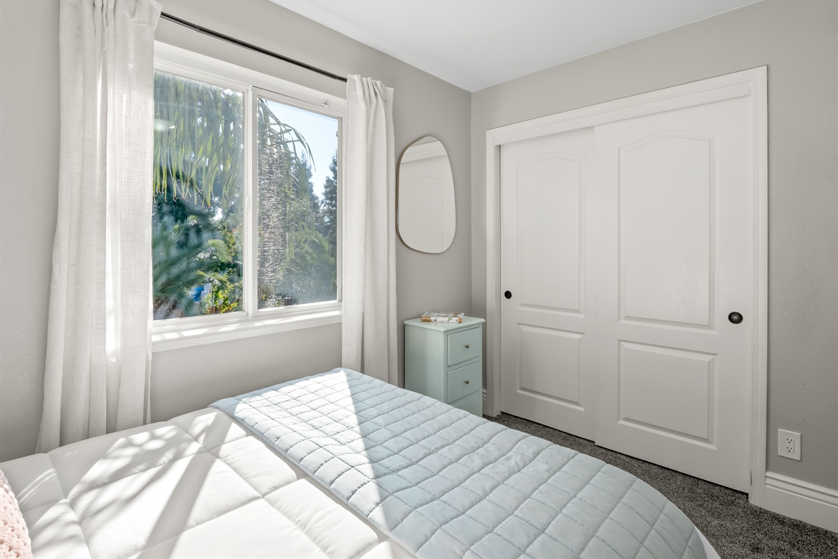 Sun-filled bedroom with a large window, soft carpeting, and ample closet space—comfortable and practical for longer family stays.