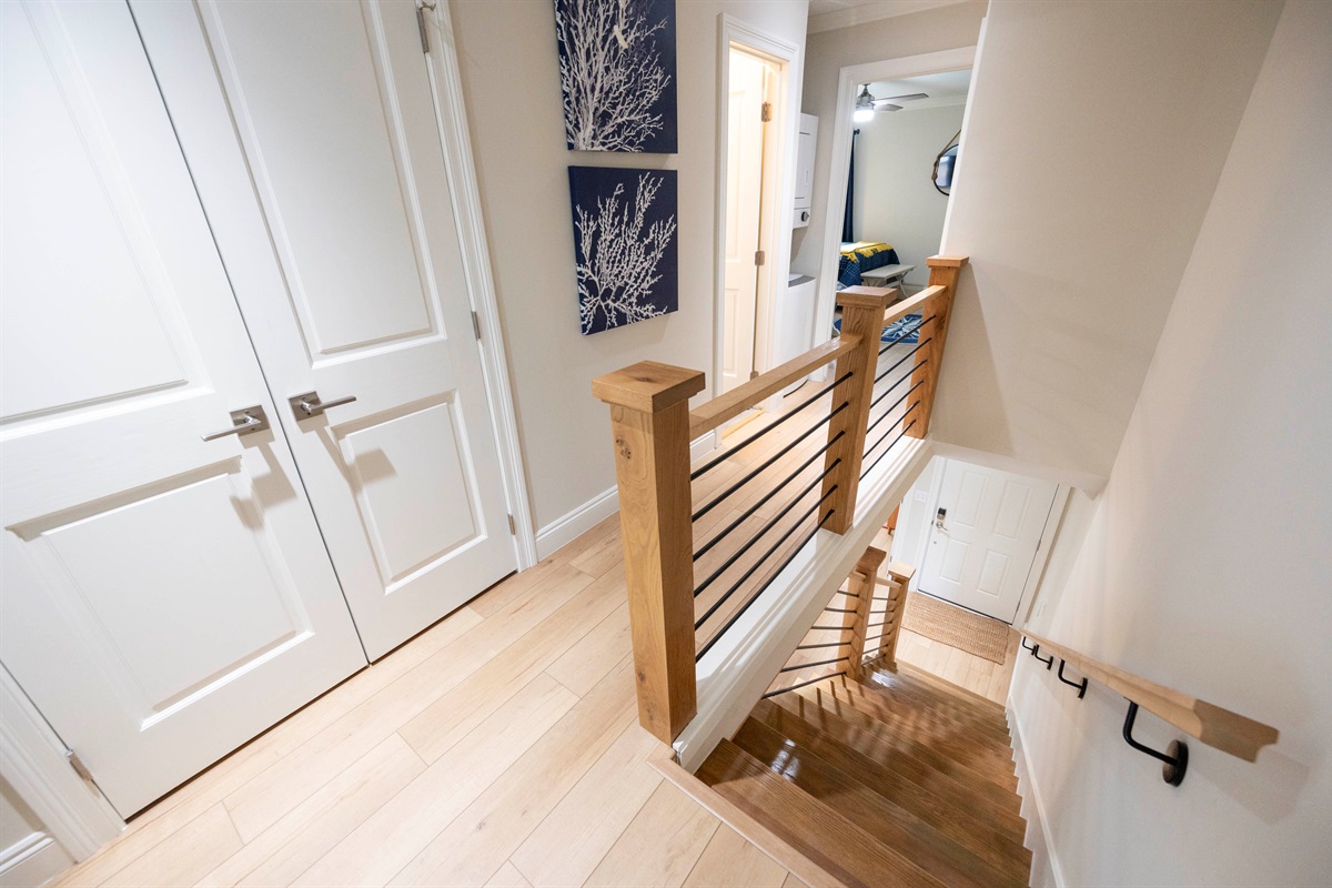 Bright and modern hallway with sleek wooden stairs, stylish decor, and easy access to rooms upstairs!