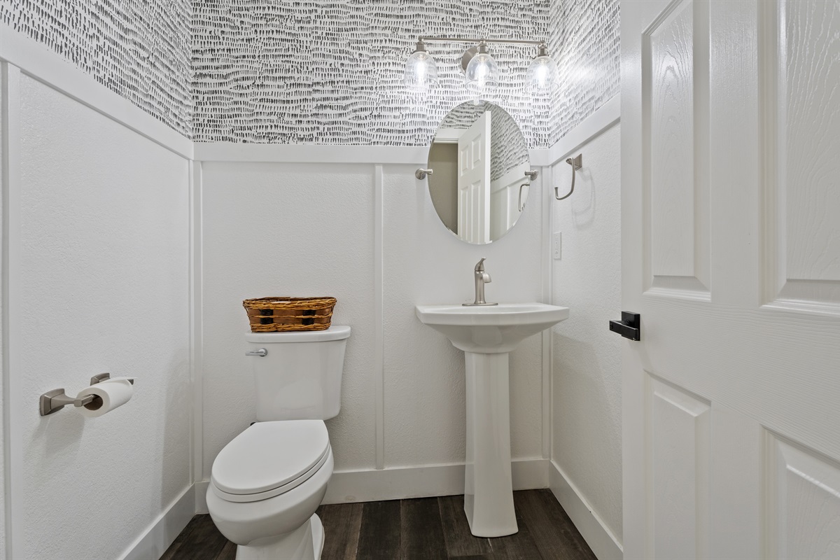 Modern and artistic, this half bath features sleek fixtures, eye-catching wallpaper, and a clean, polished design.